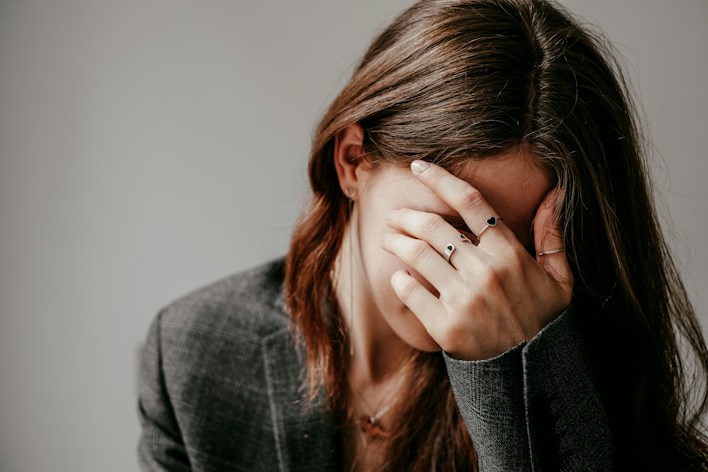 Woman covering her face with her hand in distress