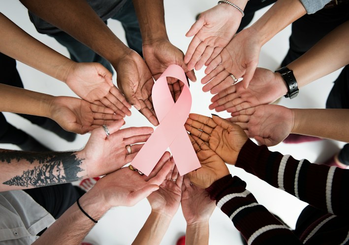Many hands joined around an awareness ribbon